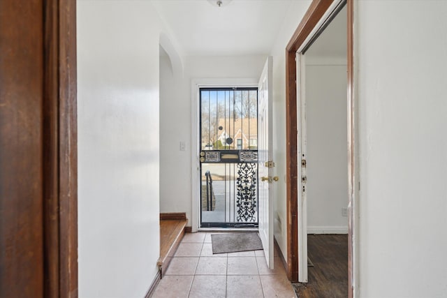 entryway featuring light tile patterned floors, baseboards, and arched walkways