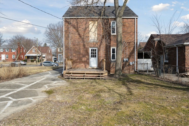 back of property with brick siding, concrete driveway, roof with shingles, and fence