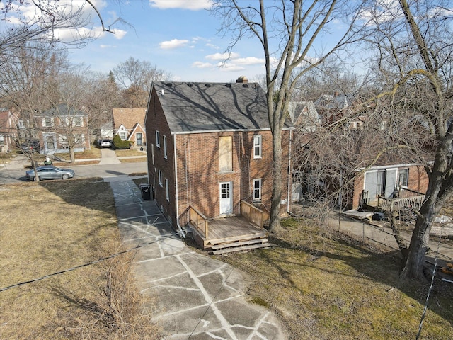 exterior space featuring brick siding, a wooden deck, and fence