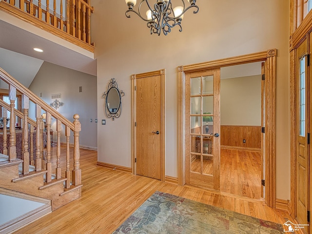 foyer entrance featuring stairs, a notable chandelier, a high ceiling, and wood finished floors