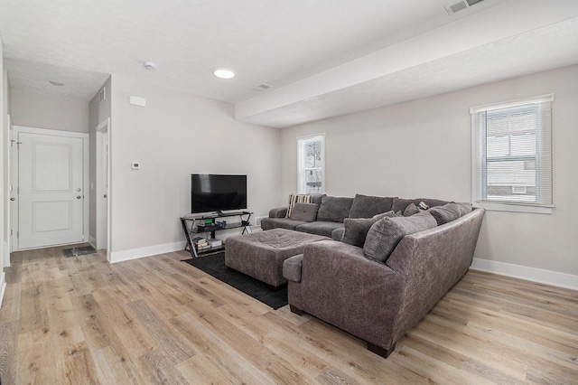 living room with light wood-style flooring, visible vents, and baseboards