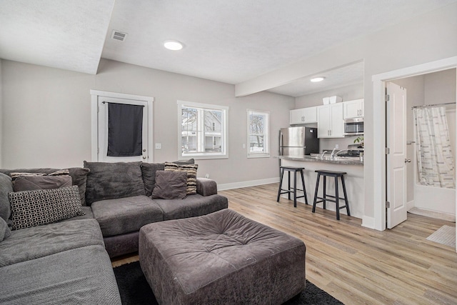 living area with light wood-type flooring, baseboards, and visible vents