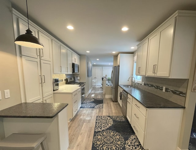 kitchen with stainless steel appliances, light wood-type flooring, a sink, and white cabinetry