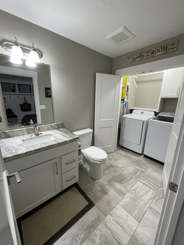 bathroom featuring toilet, visible vents, vanity, marble finish floor, and washer and clothes dryer