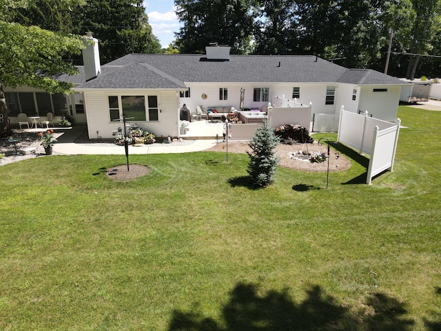 rear view of property featuring a yard, a chimney, a patio, and fence