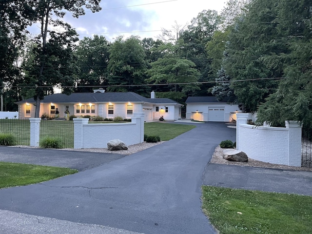 single story home featuring a garage, a fenced front yard, a front yard, and an outbuilding