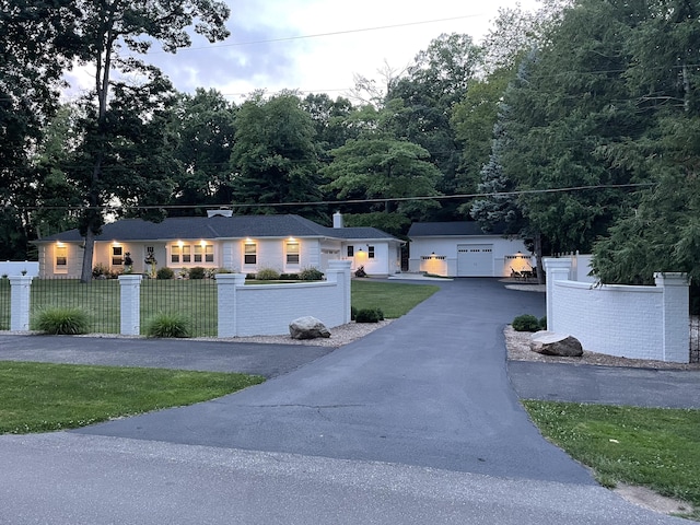 ranch-style home with an outbuilding, aphalt driveway, a fenced front yard, a garage, and a front lawn