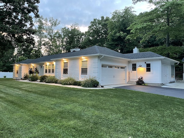 ranch-style home with an attached garage, brick siding, driveway, a chimney, and a front yard