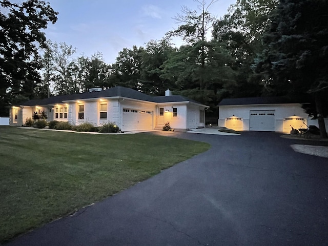 ranch-style home with aphalt driveway, a garage, and a front lawn