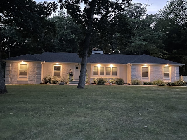 ranch-style home with a chimney, a front lawn, and brick siding