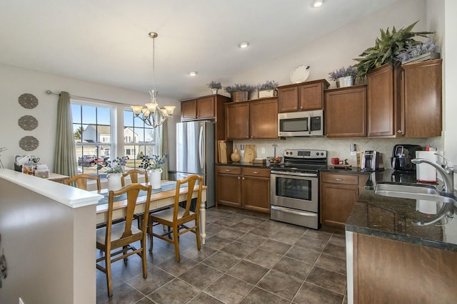 kitchen featuring decorative backsplash, a sink, stainless steel appliances, pendant lighting, and a notable chandelier