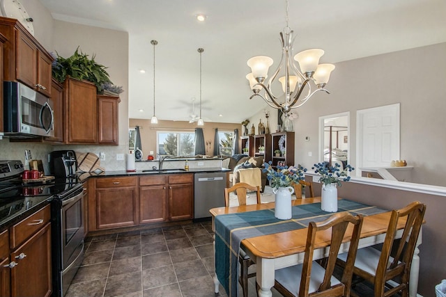 kitchen with stainless steel appliances, dark countertops, backsplash, a sink, and a peninsula