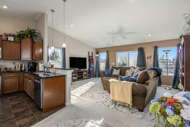 kitchen featuring a peninsula, a sink, open floor plan, stainless steel dishwasher, and dark countertops