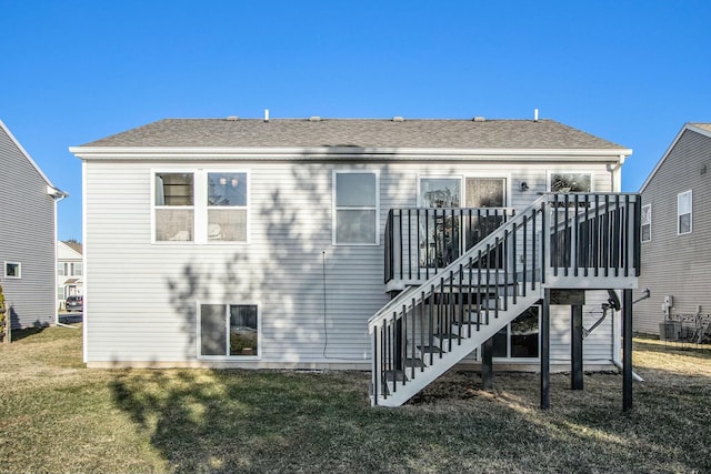 rear view of property with a shingled roof, stairs, a deck, and a lawn