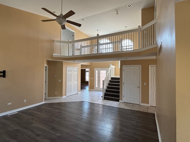 unfurnished living room featuring stairway, a ceiling fan, wood finished floors, visible vents, and baseboards