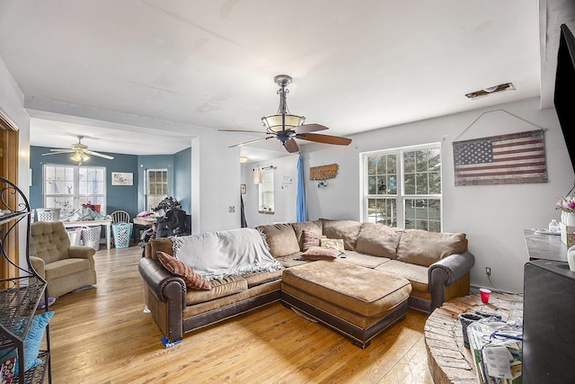 living area featuring visible vents, ceiling fan, and light wood finished floors