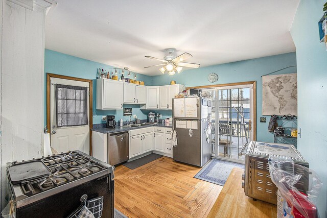 kitchen with stainless steel appliances, a sink, a ceiling fan, white cabinets, and dark countertops