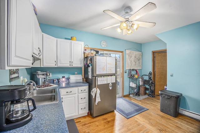 kitchen featuring light wood-style floors, freestanding refrigerator, white cabinetry, and a sink