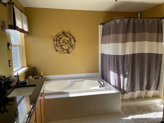 bathroom with tile patterned floors, a shower with shower curtain, a bath, and vanity