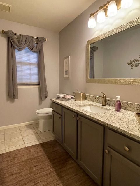 bathroom with tile patterned flooring, visible vents, baseboards, toilet, and vanity