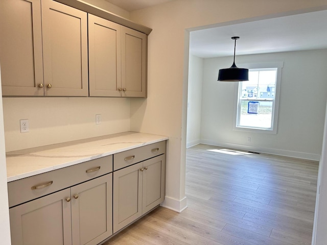 1846 Round Barn Dr, Hudsonville, MI 49426 - kitchen featuring gray cabinetry, light wood-style floors, light stone counters, and pendant lighting