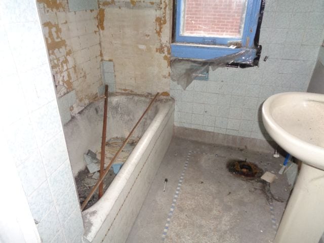 bathroom featuring tile walls and a bath