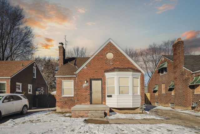 bungalow with a chimney and brick siding