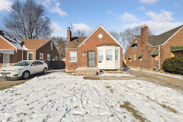 bungalow-style house with a chimney and brick siding