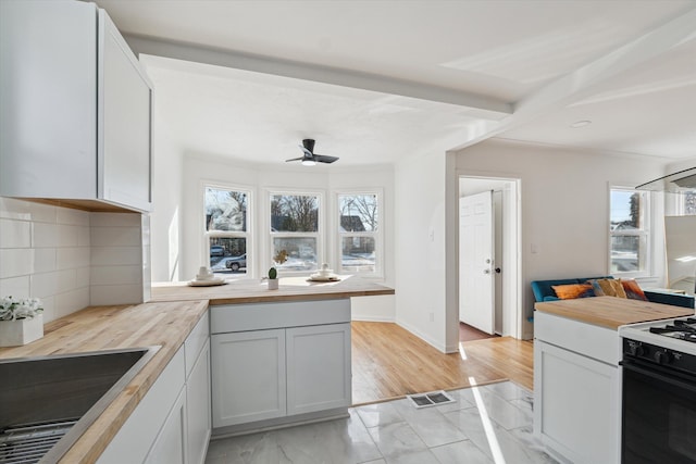 kitchen featuring tasteful backsplash, a healthy amount of sunlight, visible vents, and gas range