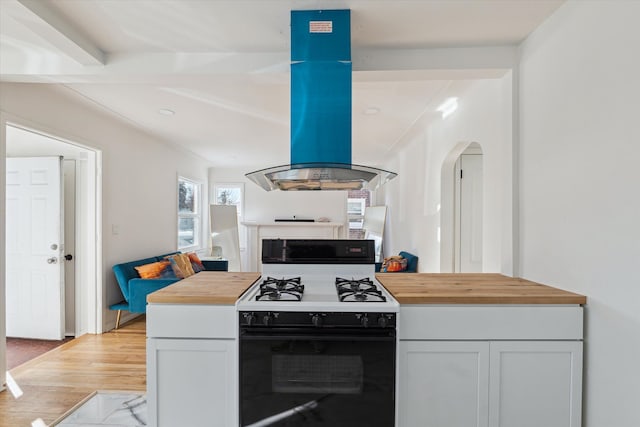 kitchen featuring arched walkways, range with gas cooktop, wooden counters, and island range hood