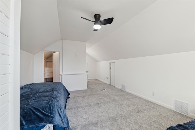 carpeted bedroom featuring vaulted ceiling, a walk in closet, visible vents, and baseboards