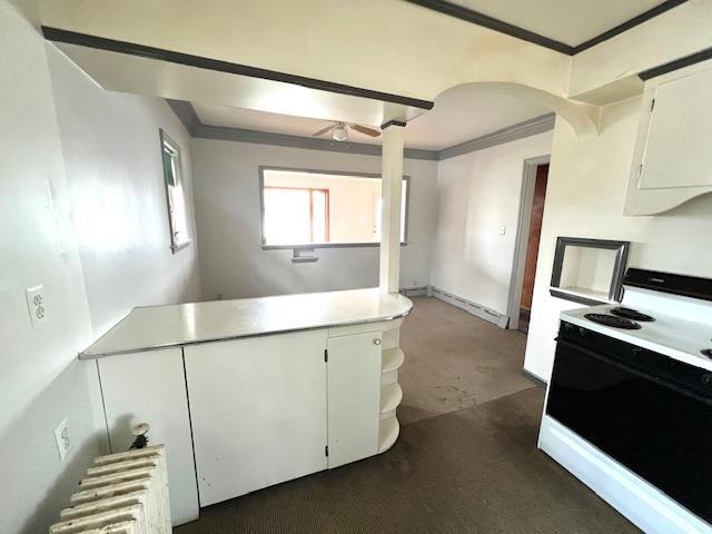 kitchen featuring electric range, white cabinets, light countertops, radiator, and crown molding