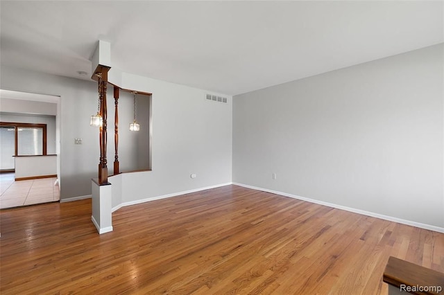 empty room with baseboards, visible vents, and wood finished floors