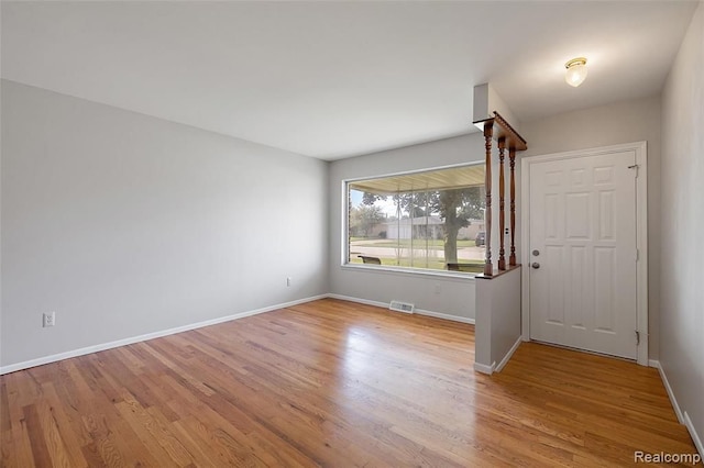 foyer with light wood finished floors, visible vents, and baseboards