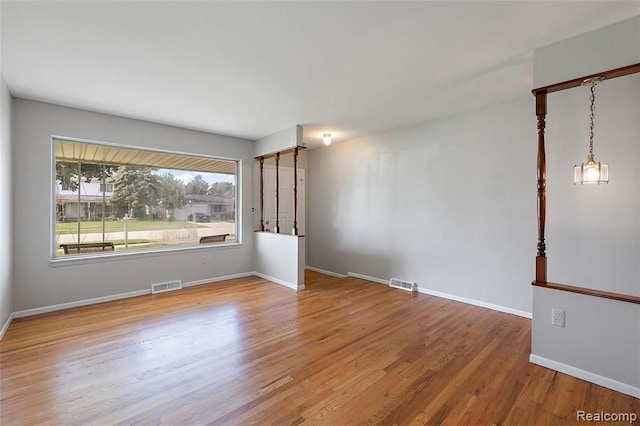 spare room featuring wood finished floors, visible vents, and baseboards