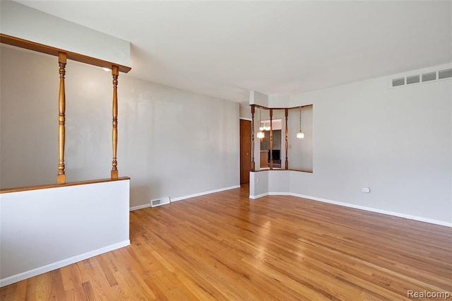 empty room with visible vents, light wood-style flooring, and baseboards