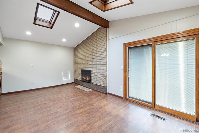 unfurnished living room with a fireplace, visible vents, lofted ceiling with skylight, wood finished floors, and baseboards