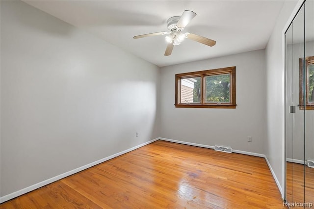 unfurnished room featuring ceiling fan, light wood-type flooring, visible vents, and baseboards