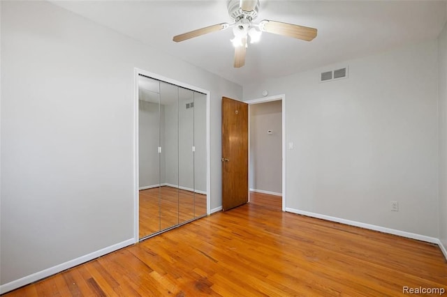 unfurnished bedroom with baseboards, a closet, visible vents, and wood finished floors