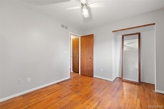 unfurnished bedroom with baseboards, a closet, visible vents, and wood finished floors