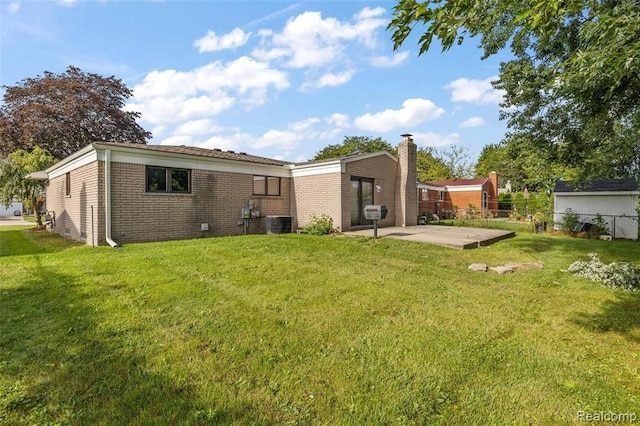 rear view of property featuring a chimney, fence, a yard, a patio area, and brick siding