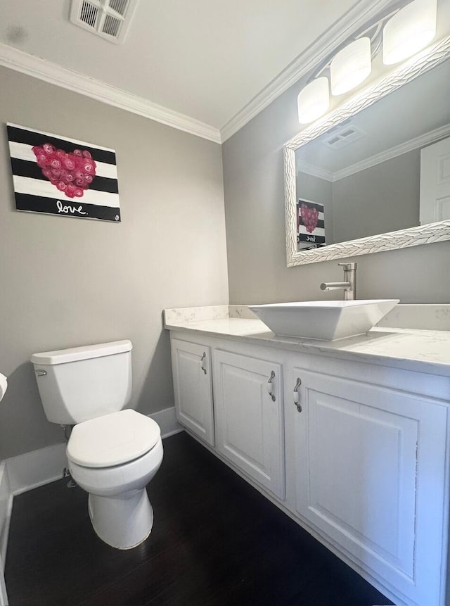 bathroom with visible vents, toilet, ornamental molding, wood finished floors, and vanity