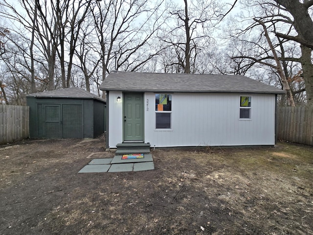 view of outbuilding with entry steps, fence, and an outbuilding