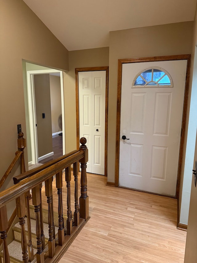 foyer entrance with light wood-style flooring and vaulted ceiling