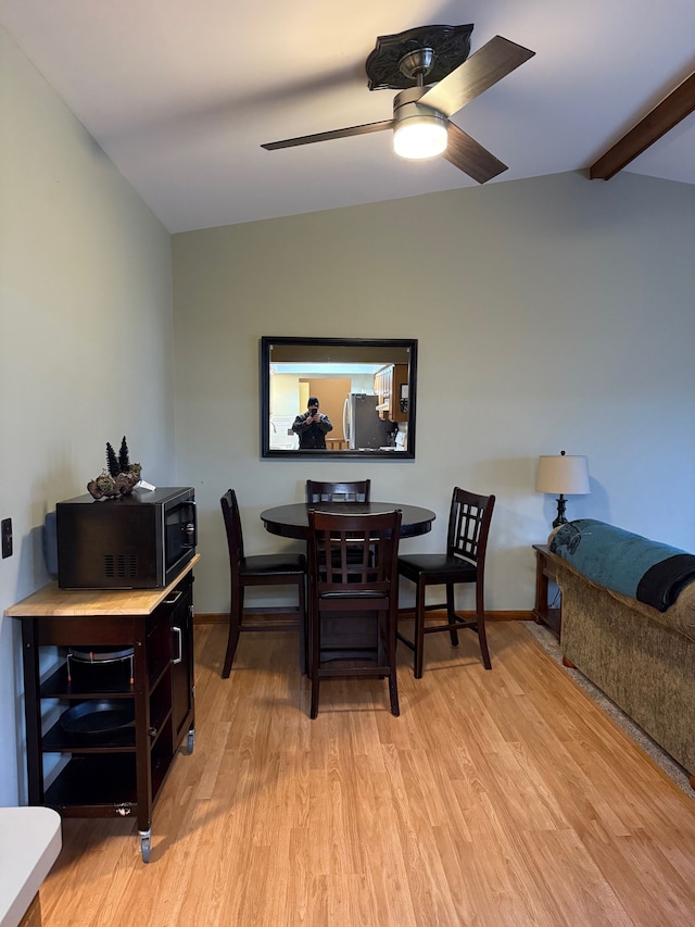 dining space featuring light wood-type flooring, ceiling fan, lofted ceiling with beams, and baseboards