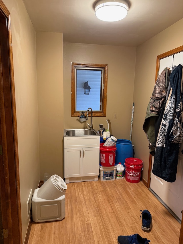 washroom featuring hookup for a washing machine, light wood-style flooring, cabinet space, and a sink