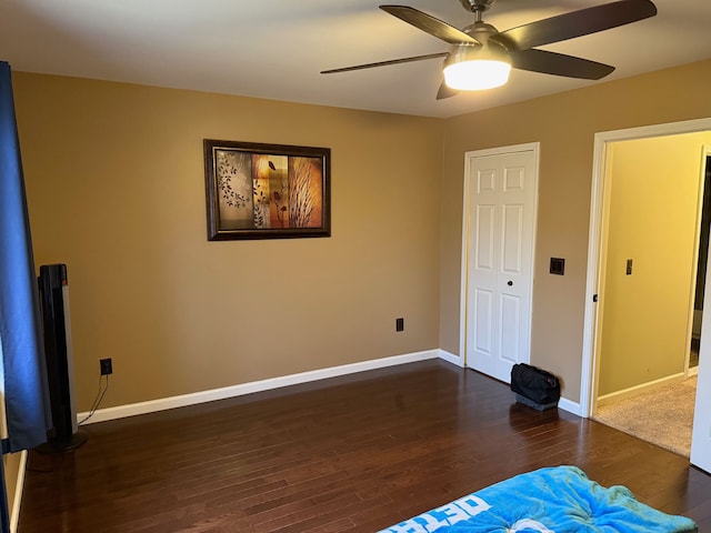 unfurnished bedroom featuring dark wood-type flooring, ceiling fan, and baseboards