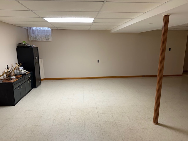 finished basement featuring light floors, baseboards, and a drop ceiling