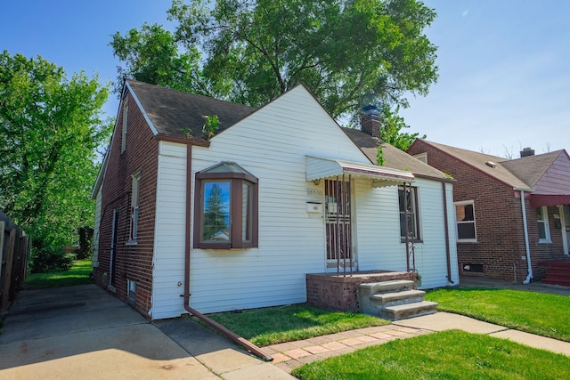 bungalow-style house featuring a shingled roof, a chimney, fence, a front yard, and brick siding