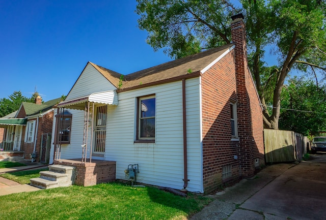 bungalow-style house featuring a front yard, brick siding, fence, and a chimney